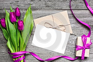 Blank white greeting card and envelope with purple tulips and gift box
