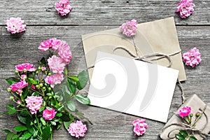 Blank white greeting card with pink rose flowers bouquet and envelope with flower buds and gift box