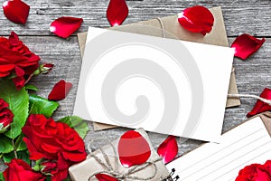 Blank white greeting card with red rose flowers bouquet and envelope with petals, lined notebook and gift box