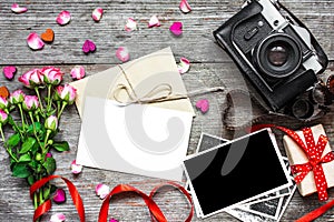 Blank white greeting card with retro camera, blank photo, gift box and pink roses