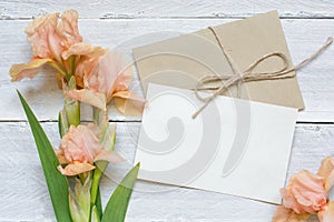 Blank white greeting card with tender iris flowers bouquet and envelope