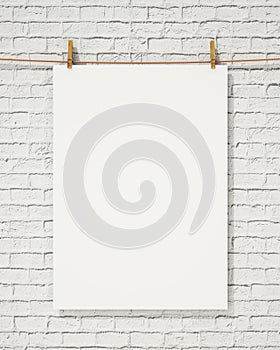 Blank white hanging poster with clothespin and rope on brick wall, background