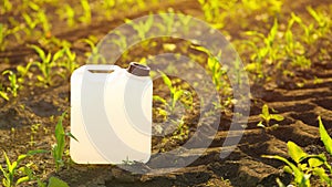 Blank white herbicide canister can in corn seedling field in springtime sunset