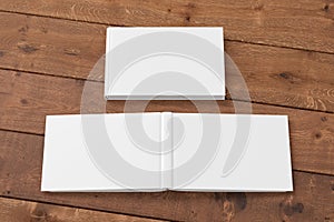 Blank white horizontal closed and open and upside down book cover on wooden boards isolated with clipping path around cover.
