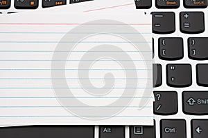 Blank white index card on a black and silver keyboard