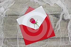 Blank white love letter and red envelope with single red rose