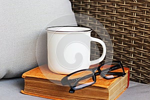Blank white mug mockup photo with book and glasses. White cup mock up for your company logo and design