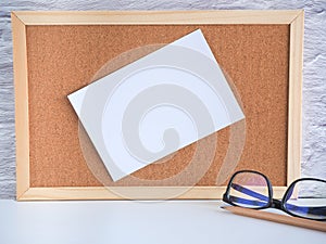 The blank white note pinned on a cork board with glasses, pencil