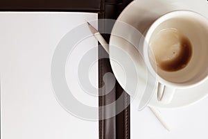 Blank white notebook, pen and cup of coffee
