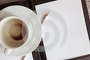 Blank white notebook, pencil and empty coffee cup