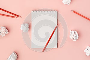 Blank white notebook with red pencils and crumpled sheets of paper