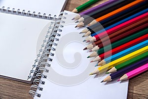 Blank white notepad with color pencil on wooden