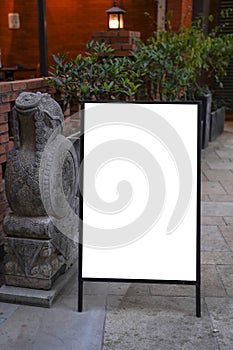 Blank white outdoor advertising stand mock up template. Clear street signage board placed against green plants.