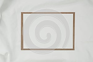 Blank white paper on brown paper envelope with white cloth. Mock-up of horizontal blank greeting card. Top view of Craft envelope