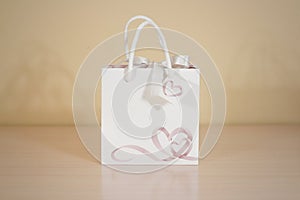 Blank white paper gift bag mock up standing on a wooden table. E