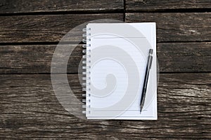 Blank white paper note book with black pencil on old wooden floor background