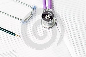 blank white paper of note book with green pen and stethoscope on medical table