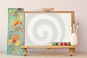 Blank white paper for painting on wooden easel on table at home studio