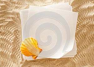 Blank white paper and seashell in sand