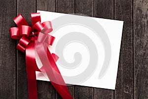 Blank white paper valentines or Christmas Greeting card with red ribbon on dark old wooden table background. picture for add text