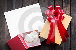 Blank white paper valentines or Christmas Greeting card with red ribbon on dark old wooden table background. picture for add text