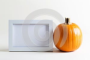 Blank white picture frame with a pumpkin