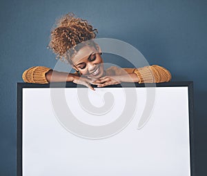 Blank white poster and copyspace of a smiling, happy and young woman holding the sign. Female looking at an empty copy