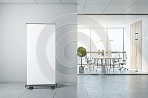 Blank white poster with copyspace on wheels in sunny office hall before workspace room with wooden decoration on light wall and