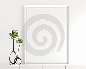 Blank white poster frame, black frame in the livingroom, elegant simple white wall, modern display cabinet, table top, white book,