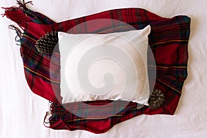 Blank white rectangle cushion laying on a tartan/plaid scarf