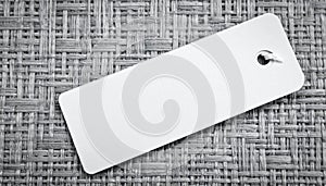 Blank white rectangular tag with string on woven textured background label empty