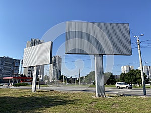 Blank white road billboard in city in summer sunny day. Street advertising poster, mock up, Glued paper mockup