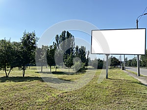 Blank white road billboard in city in summer sunny day. Street advertising poster, mock up, Glued paper mockup
