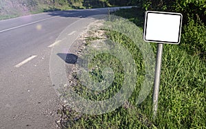 A blank white road sign next to the highway.