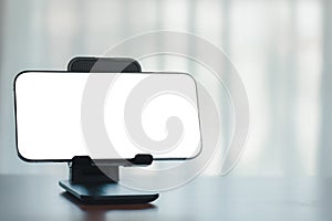 Blank white screen smartphone on wooden table with blur background in office room