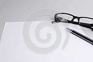Blank white sheet of paper,pen and a glasses photo
