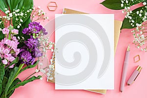Blank white sheet on spiral golden notepad with pen for your text or design and bouquet of flowers on pink background. Concept
