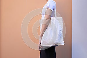 Blank white shopping canvas fabric cloth bag on female holding mockup and template isolated color background