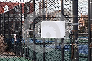 Blank white sign on a metal chain link fence by a playground