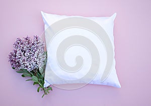 Blank white square cushion on pink background with lilac flowers to the left