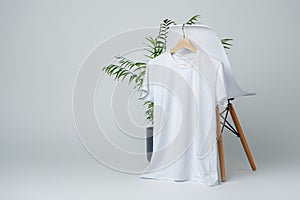 Blank white T-shirt hanging on a chair on white background