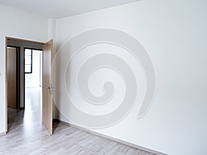 Blank white wall background in the empty room near the wooden opened door with copy space