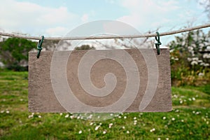 Blank wooden board hanging on rope in countryside. Space for text