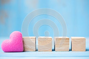 Blank wooden cubes with pink heart shape decoration on blue table background and copy space for text. Love, Romantic and Happy