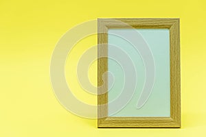 Blank wooden frame on yellow background. Flat lay. Copy space. Top view