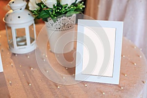 Blank wooden picture frame decoration on table decorated by white tablecloth. Wedding reception ceremony, anniversary celebration