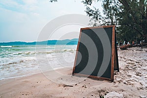 blank wooden sign on beach. Black Board for writing menu chalk on white sand on beach on tropical exotic island