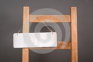 Blank wooden sign is hanging on a chair, welcome and sale concept, copy space for text, open and closed business