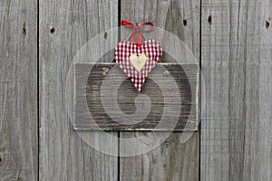 Blank wooden sign with red gingham and gold hearts hanging on wood background