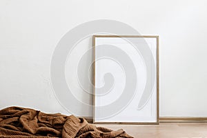 Blank wooden vertical picture frame mock-up on floor. Cinnamon linen plaid. White wall background. Empty copy space, no